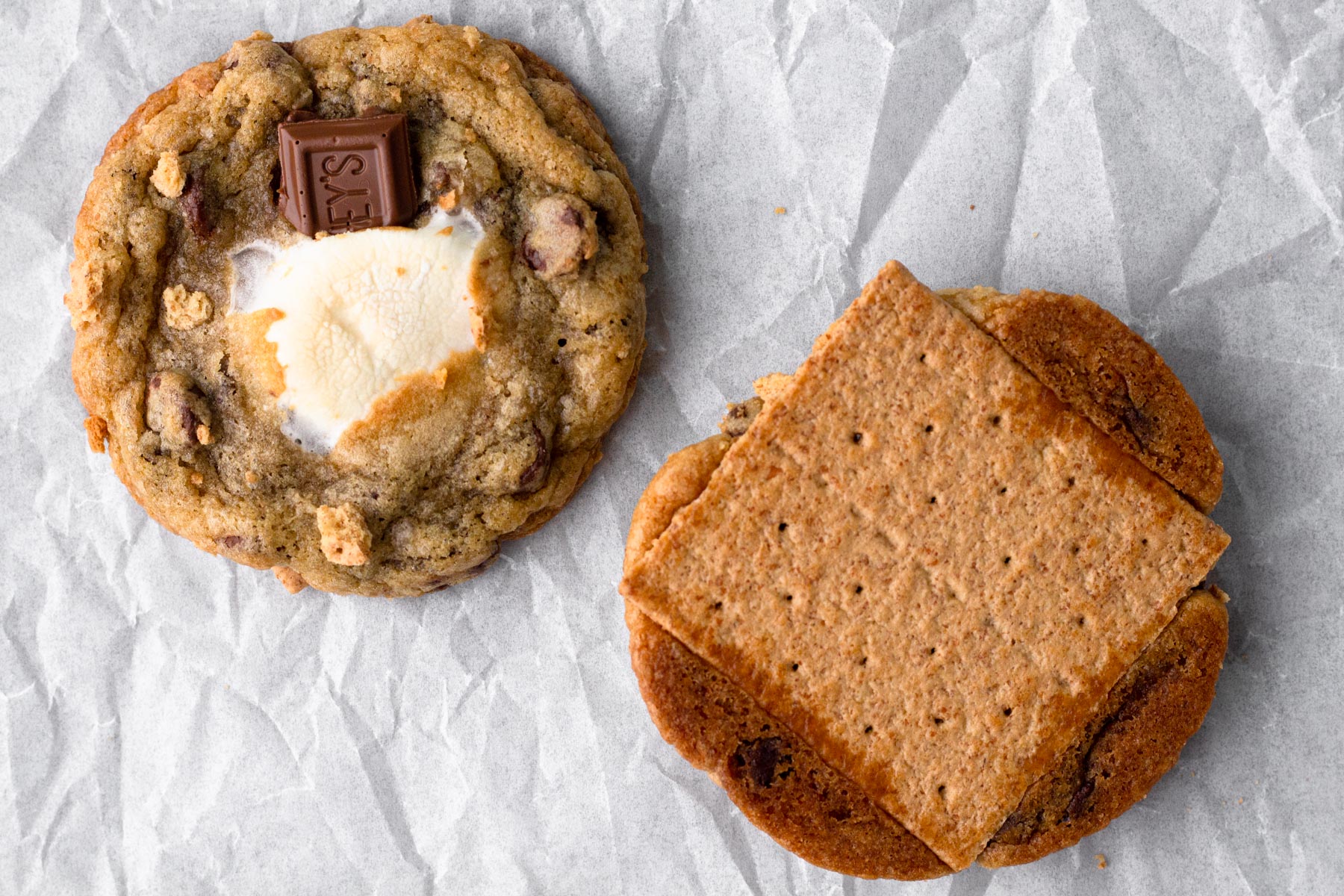 Two s'mores cookies, one with toasty marshmallow and chocolate and the other one upside down with a graham cracker base.