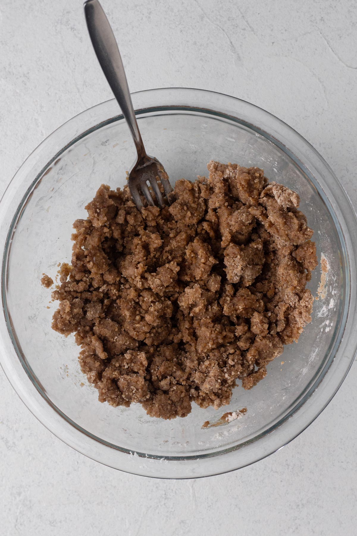 Crumb topping in a glass bowl with a fork.