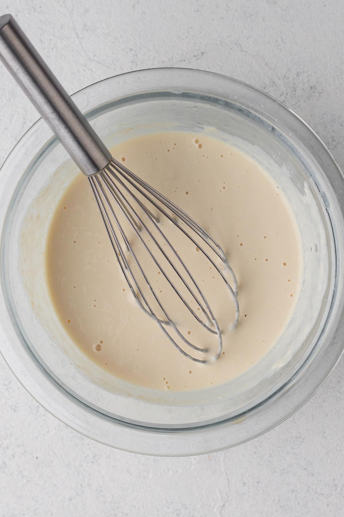 Wet ingredients whisked together in a glass mixing bowl.