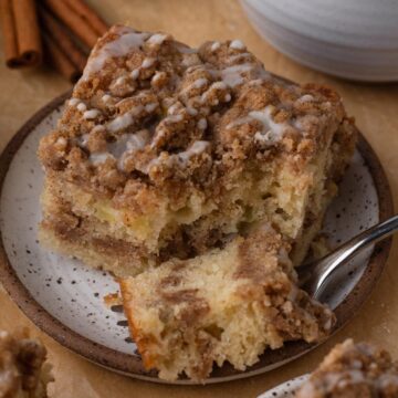 A slice of coffee cake with a forkful of cake on a white plate.