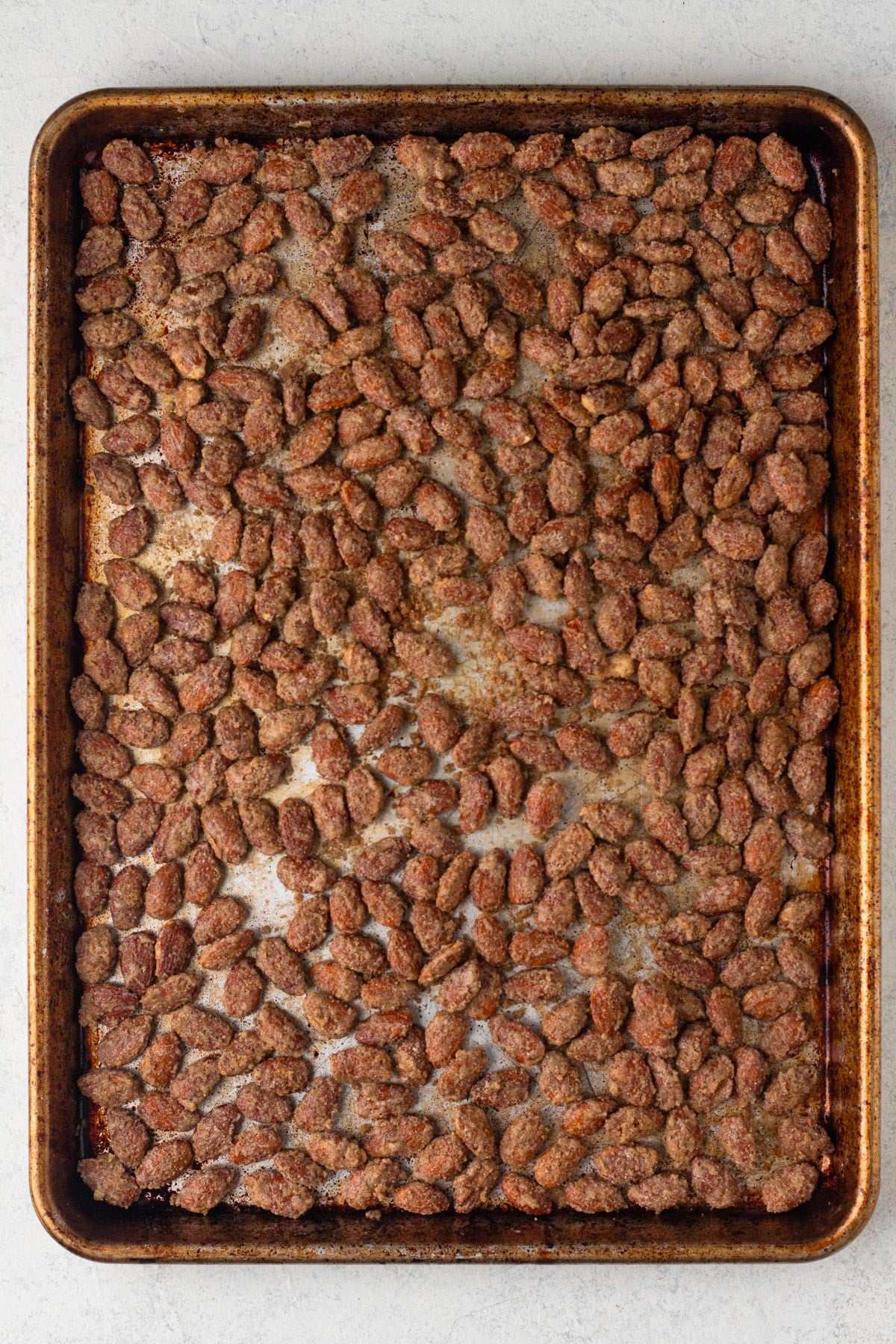 Baked candied almonds on a metal baking sheet.