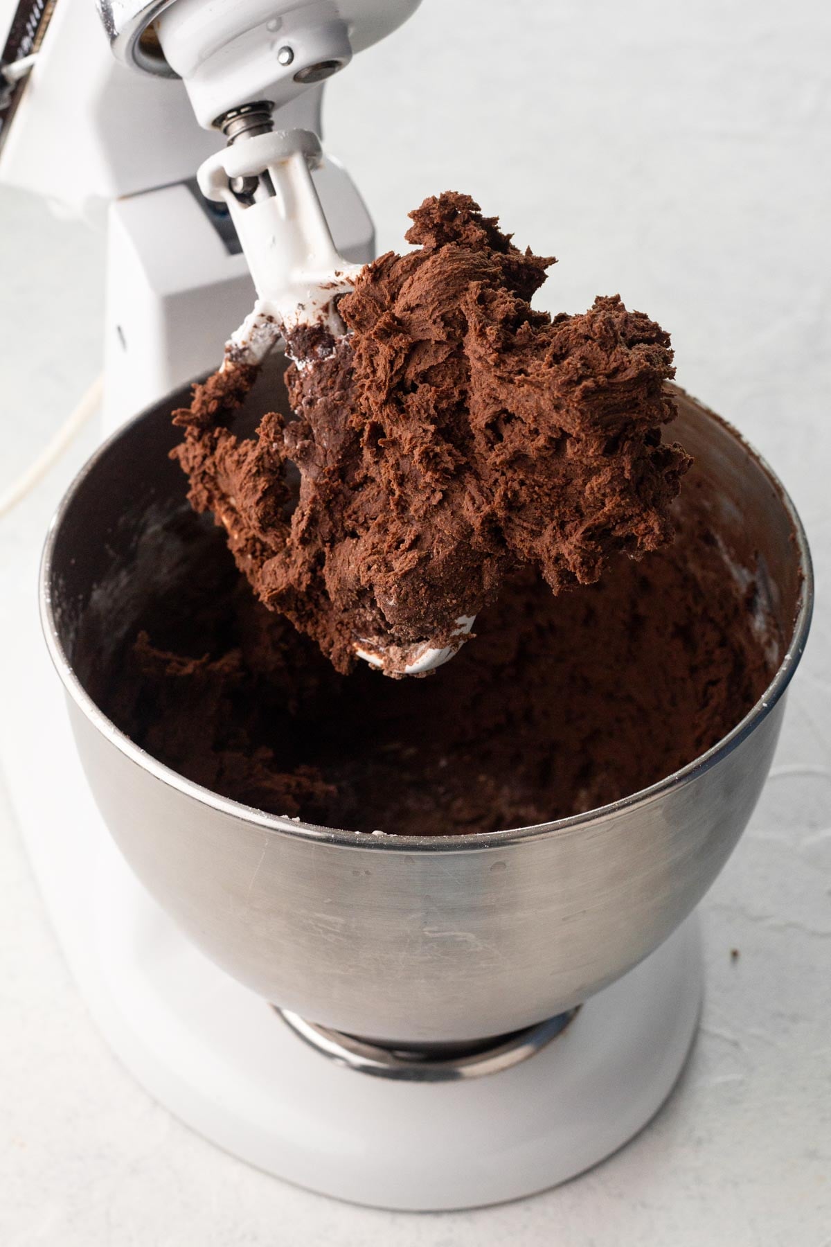 Butter beaten with cocoa powder and powdered sugar in the bowl of a stand mixer.