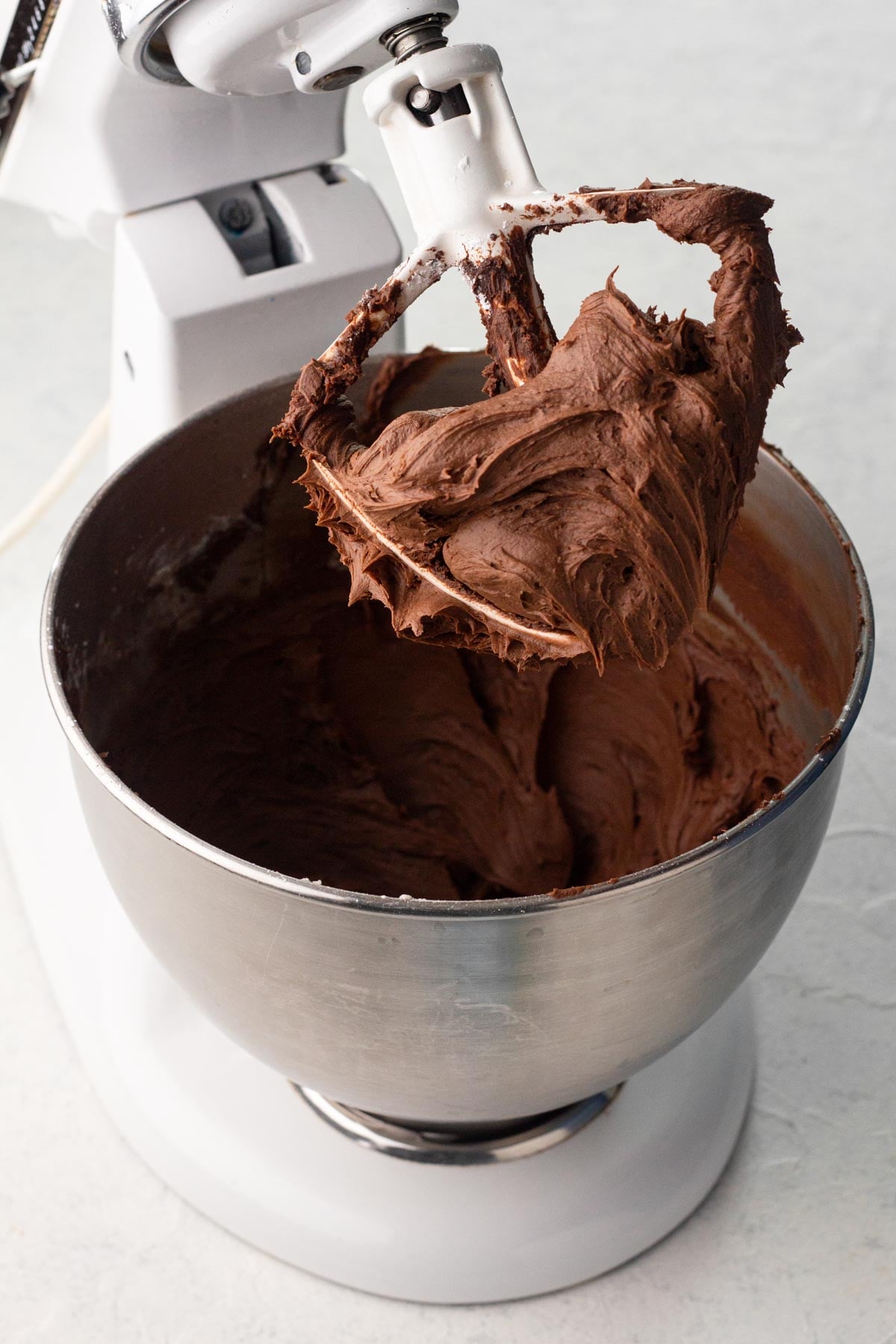 Chocolate frosting in the bowl of a stand mixer.