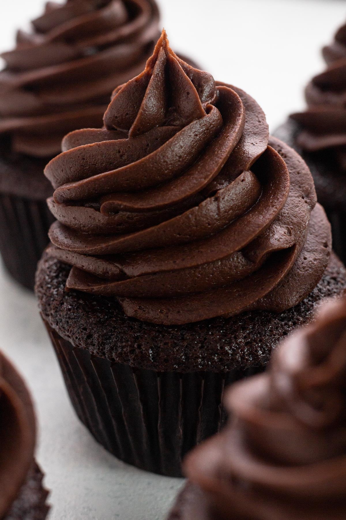 A tall swirl of chocolate frosting on top of a chocolate cupcake.