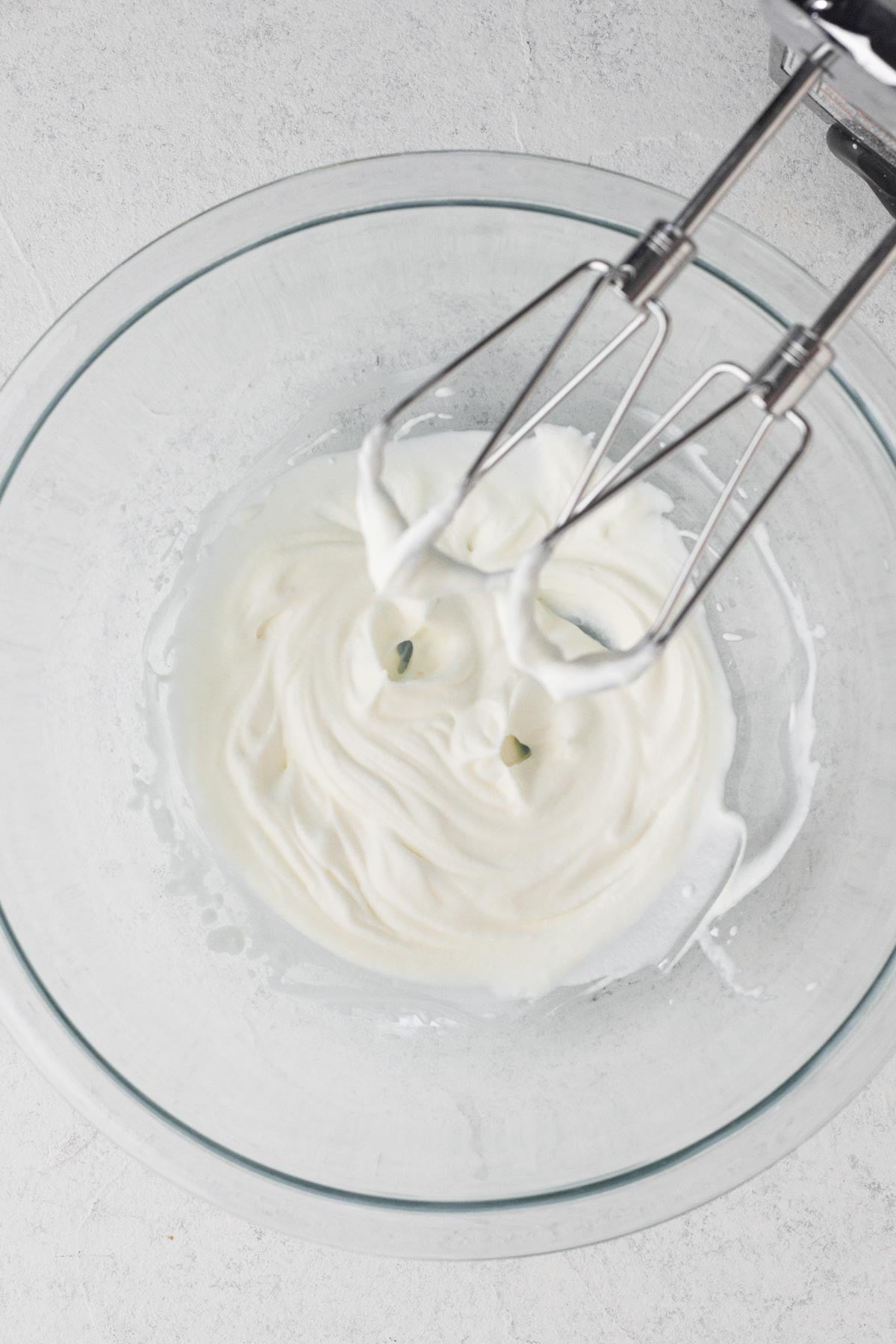 Whipped cream topping whipped to stiff peaks in a glass mixing bowl.