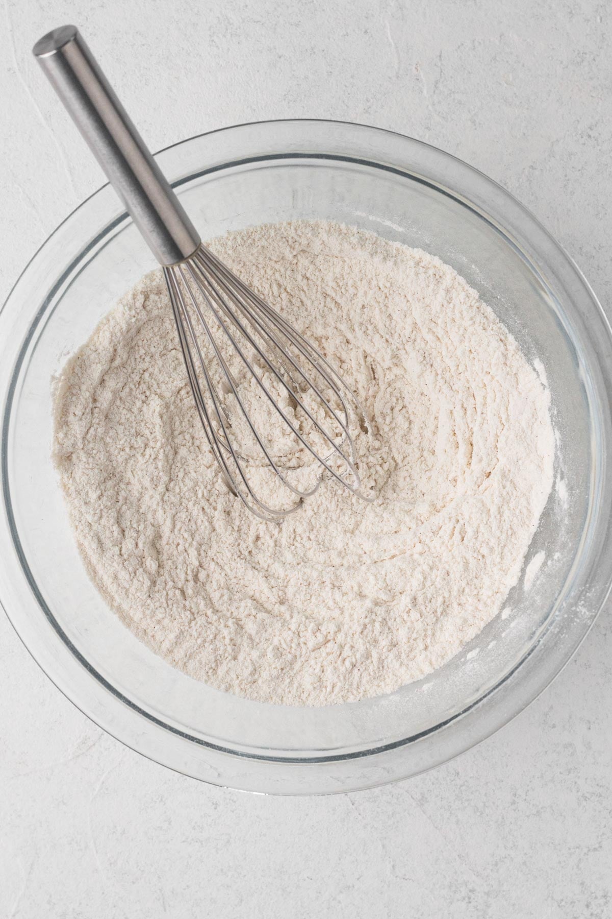 Sugar cookie dough dry ingredients whisked together in a glass bowl.