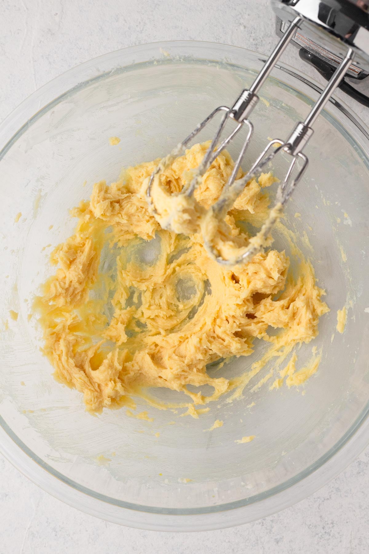 Sugar cookie dough wet ingredients blended together in a glass mixing bowl.