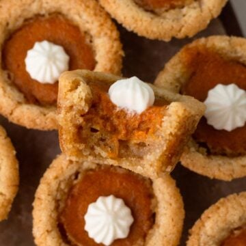 A bitten sugar cookie cup with pumpkin pie filling and whipped cream.