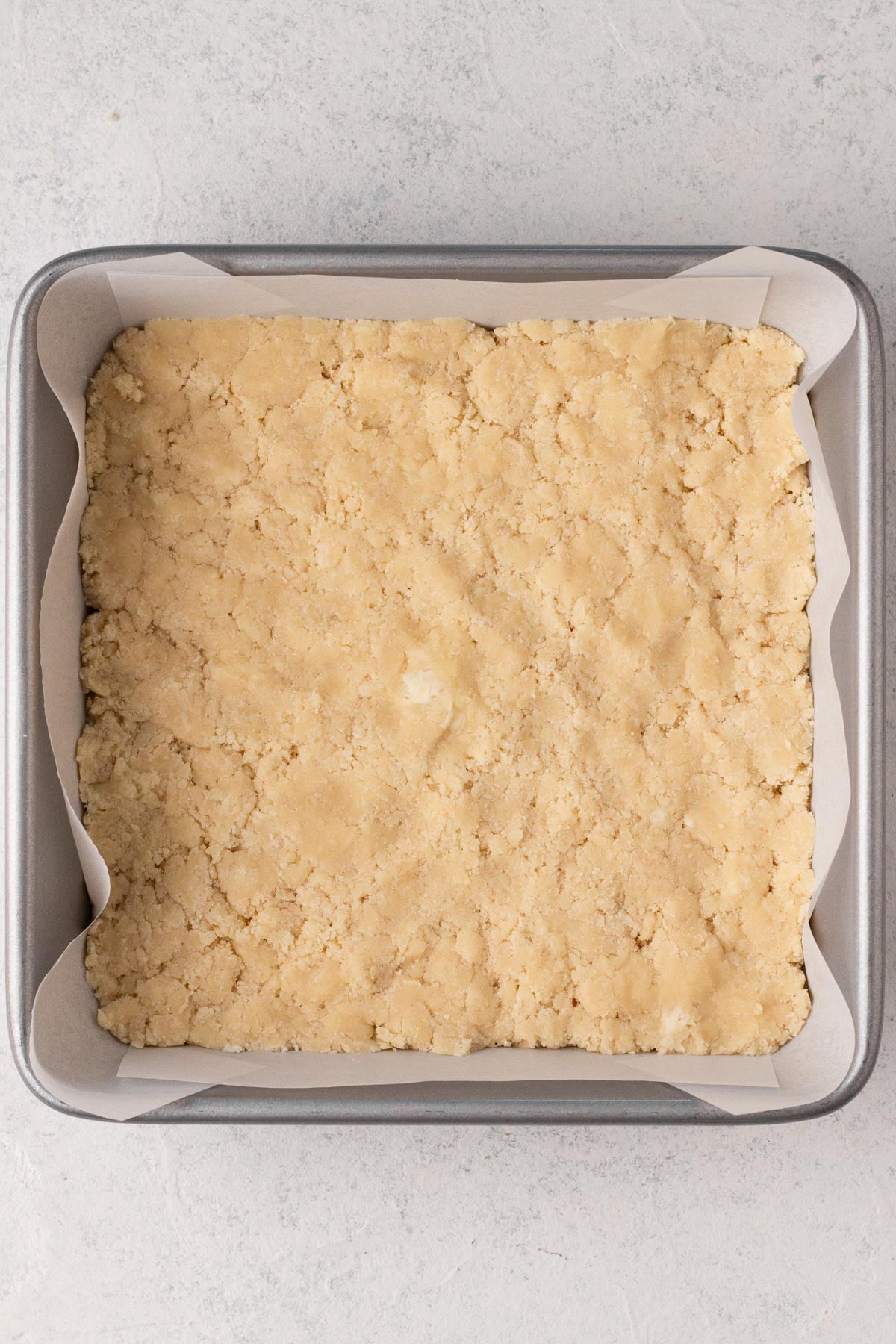 Shortbread cookie dough pressed into a square metal pan.