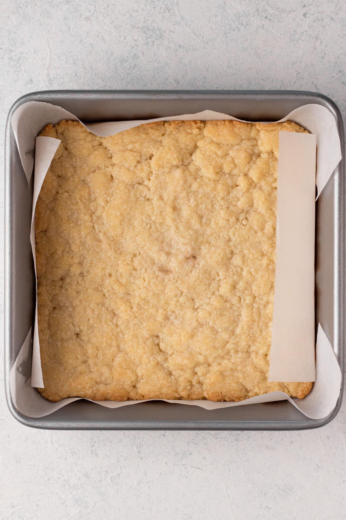Par-baked shortbread crust in a square metal pan.