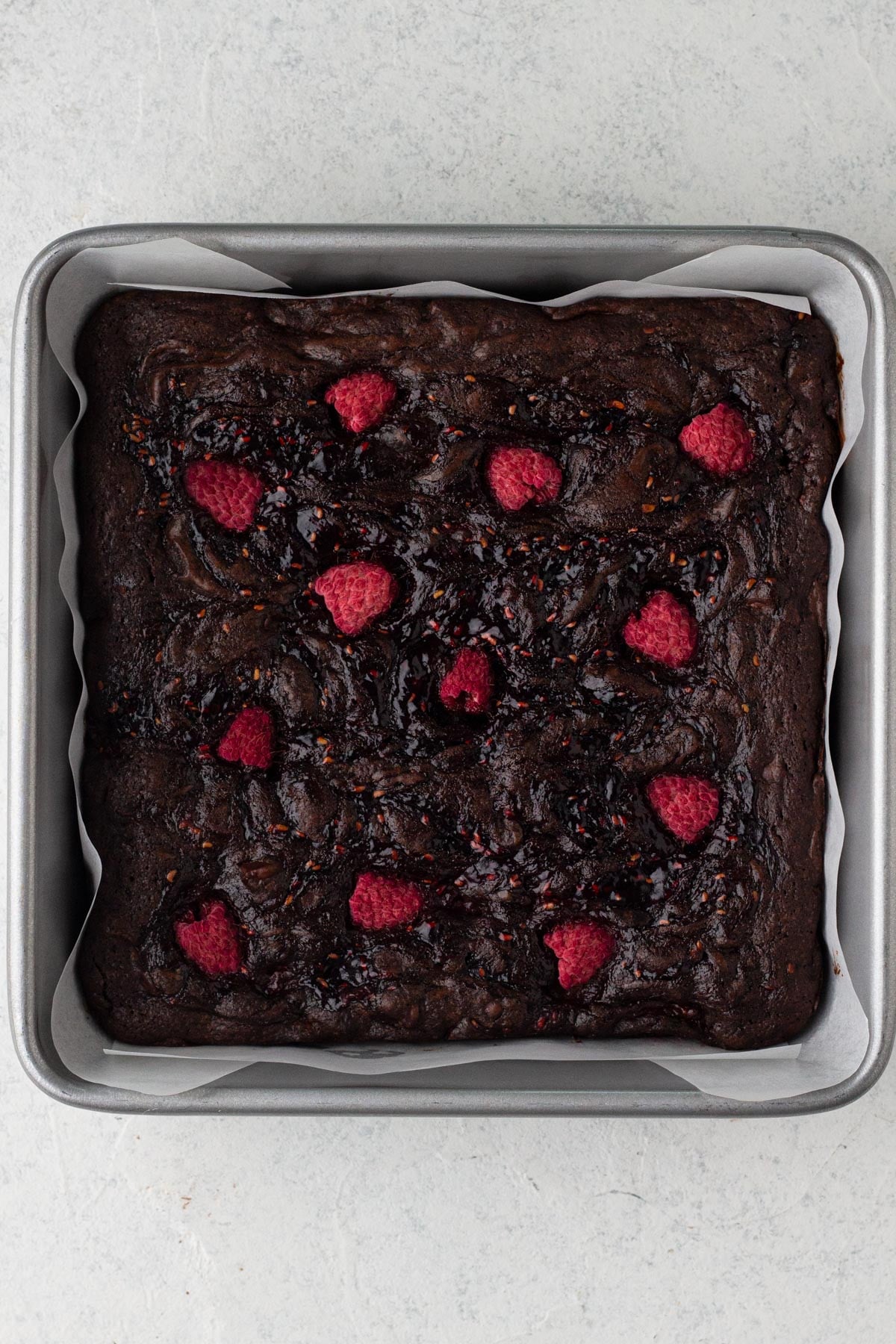 Baked brownies with fresh raspberries in a square baking pan.