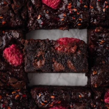 Close-up side view of a chocolate brownie with fresh raspberries.